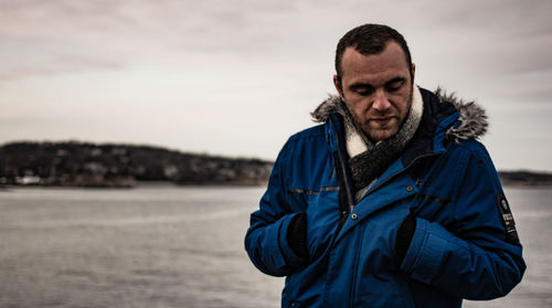 Man standing at beach against sky during winter