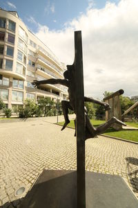 Man by footpath in city against sky