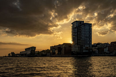 River by buildings against sky at sunset