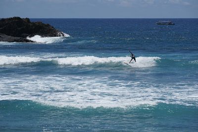 Man surfing in sea against sky