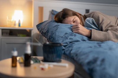 Close-up of medicine while sick woman resting in background