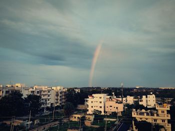 Rainbow over buildings in city against sky