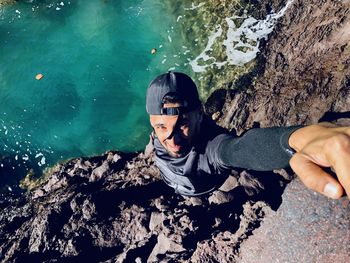 Low angle view of young man standing against waterfall