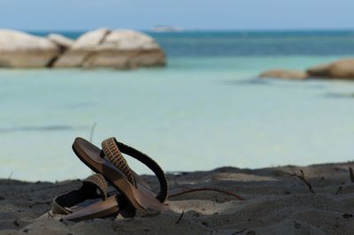 Sandals on beach against sky