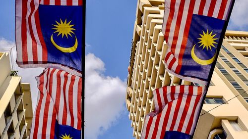 Low angle view of flags hanging against blue sky