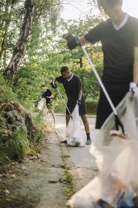 Teenage boys collecting plastic in garbage bags on road