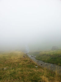 Scenic view of landscape against sky during foggy weather