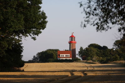 Lighthouse amidst trees against sky