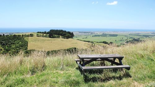 Bench on field against sky