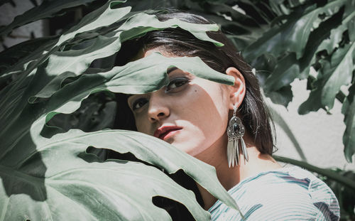 Close-up portrait of confident young woman standing amidst plants