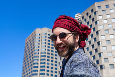 Portrait of man wearing sunglasses against blue sky