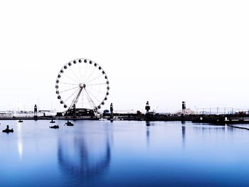 Ferris wheel in sea against clear sky