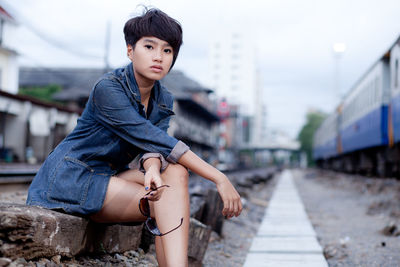 Portrait of fashionable woman sitting on railroad track