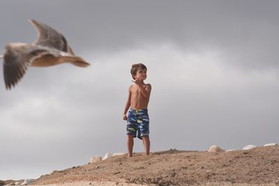 Low angle view of young woman standing against sky