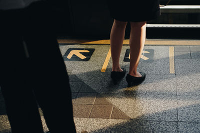 Low section of woman standing at railroad station platform