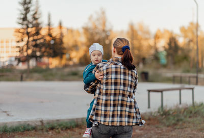 Woman holds a child with down syndrome in her arms outdoors