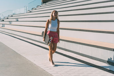 Beautiful stylish woman with her longboard in the park.