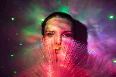 Close-up portrait of young woman by illuminate lights