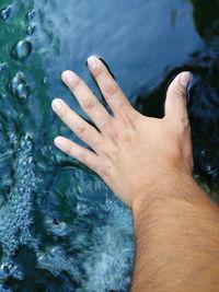 Close-up of hand touching water surface in river