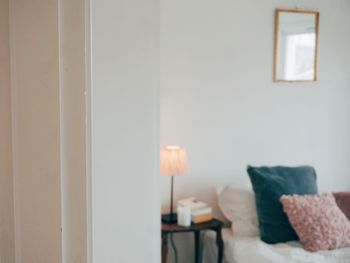 A white door in focus with a bedroom with double bed in blurred background 