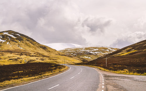 Country road against cloudy sky