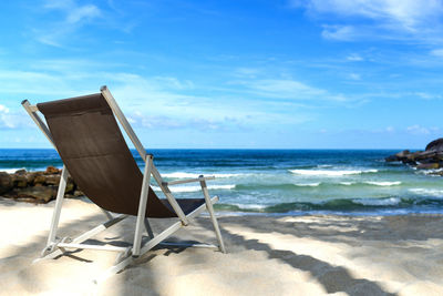 Chair on beach against blue sky