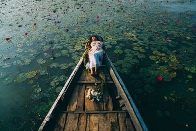 High angle view of woman lying on boat in lake