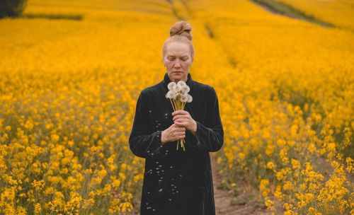Young women  standing amidst yellow flowering plants on field