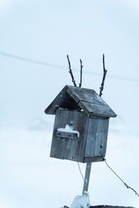 Low angle view of birdhouse on snow covered field against sky
