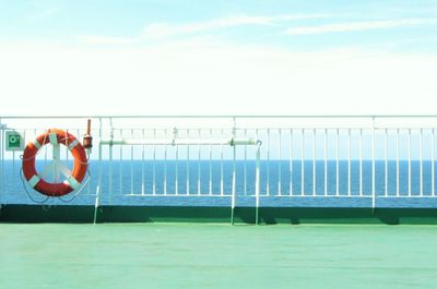 Clothes hanging on railing by sea against sky