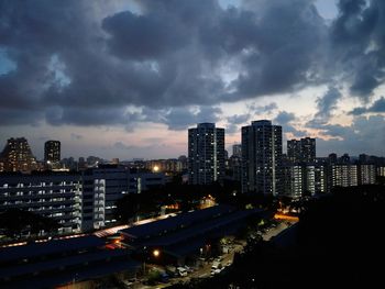 Aerial view of city lit up against cloudy sky