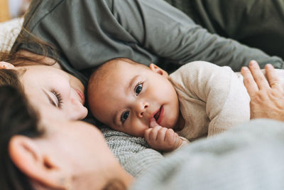 Real family of young mom and two kids of different ages teenager girl and baby boy having fun on bed