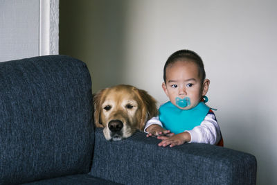 Cute boy with dog by sofa at home