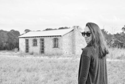 Young woman wearing sunglasses standing on field