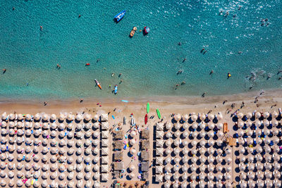 Aerial view of people and beach umbrellas by sea