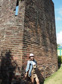 Full length of man standing against brick wall