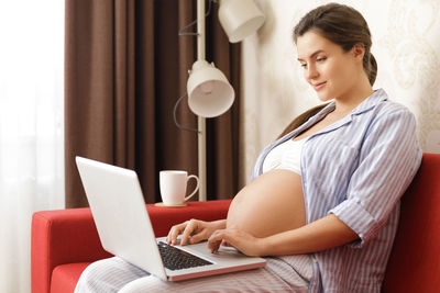 Smiling pregnant woman using laptop in office