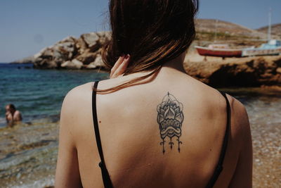 Rear view of shirtless woman at beach