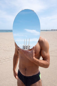 Midsection of shirtless man in sea against sky