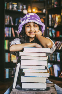 Portrait of smiling girl sitting near stack of books in bookstore