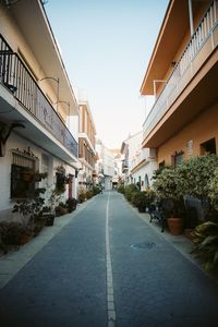 Empty road amidst buildings against clear sky