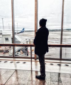 Rear view of man looking through window