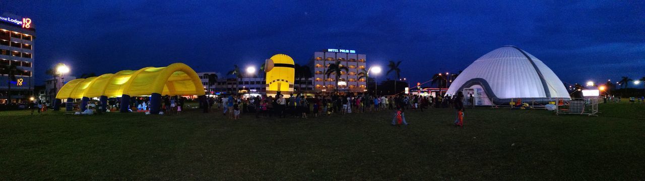 CROWD AT ILLUMINATED CITY AGAINST SKY