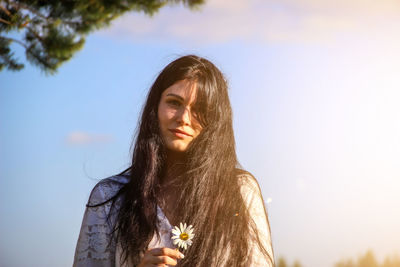 Portrait of young woman standing against sky