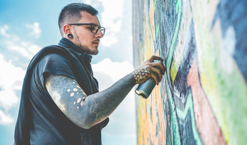 Side view of young man standing against wall