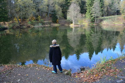 Rear view of woman standing by lake