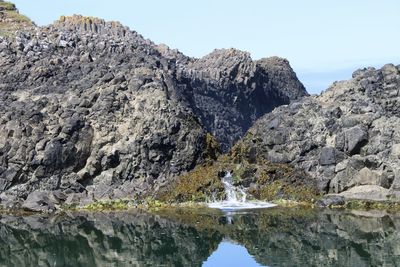 Scenic view of rocks by sea against sky