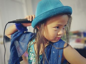 Girl holding microphone while looking away at home