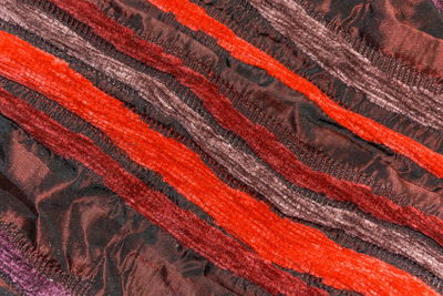 Background, texture of the burgundy silk fabric with red and purple stripes