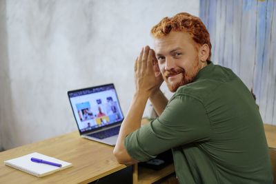 Portrait of young man using laptop while sitting on table